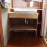 洗面台に合わせて棚を作りました。 左上の棚が微妙に斜めになっているのは、水はけを良くするため。 間口いっぱいにしてしまうとトイレの入り口と干渉してしまうので、 シュミレーションをしながら余すところなくスペースを活用しました。 手前にはお客様が好きな柄のカーテンを付けたいとおっしゃっていたので、 カーテンレールを付けました。